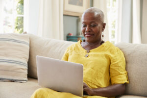 A women with dark skin sitting on couch looking working with the laptop